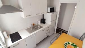 eine kleine Küche mit weißen Schränken und einem Waschbecken in der Unterkunft Sunny apartment near the beach in Santa Pola