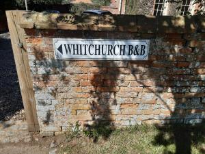 a white street sign on a brick wall at Whitchurch Farm Guesthouse in Alderminster