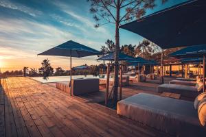 a patio with blue umbrellas and tables and benches at Charm Nature in Azoia