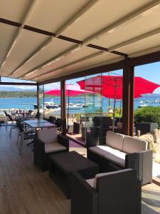 un restaurante con mesas, sillas y sombrillas rojas en Hôtel du Golfe, en Bonifacio