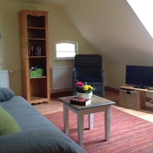ein Wohnzimmer mit einem Sofa und einem Tisch mit Blumen darauf in der Unterkunft Klaassen- Ferienhaus Up Warf in Emden