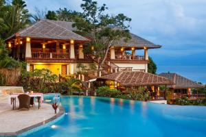 a villa with a swimming pool in front of a house at Bunaken Oasis Dive Resort and Spa in Bunaken