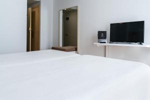 a bedroom with a white bed and a flat screen tv at Sercotel Ciudad de Cazorla in Cazorla
