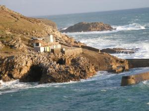 a building on a cliff next to the ocean at Les chambres d'hotes du cosquer in Beuzec-Cap-Sizun