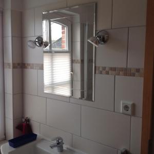 a bathroom with a sink and a mirror at Klaassen- Ferienhaus Up Warf in Emden