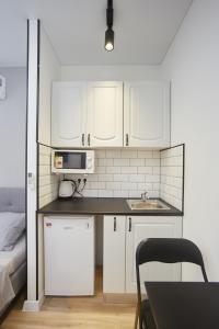 uma pequena cozinha com armários brancos e um lavatório em City Rooms Apartments em Odessa