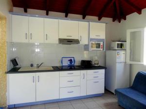 cocina con armarios blancos y sofá azul en Domaine De Berard, en Sainte-Anne