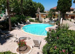 a swimming pool with a bunch of chairs around it at Splendid Hôtel in LʼÎle-Rousse
