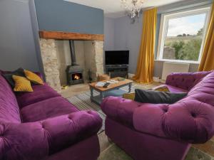 a living room with purple couches and a fireplace at The Farmhouse in Okehampton
