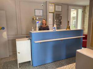 a woman standing behind a blue counter in a store at L'Amiral in Paris