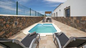 a swimming pool with two lounge chairs next to a building at Villa Elena in Lajares