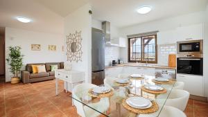 cocina y sala de estar con mesa de cristal y sillas en Villa Elena, en Lajares
