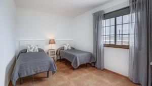 a bedroom with two beds and a window at Villa Elena in Lajares +16 photos