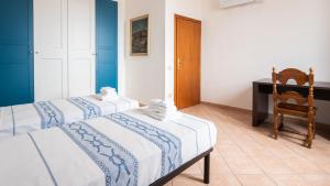 two beds in a room with a chair and a desk at Welcomely - Isole Apartments in Olbia