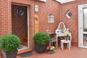 ein Backsteingebäude mit zwei Topfpflanzen auf einer Terrasse in der Unterkunft Ferienwohnung Sonnenberg, 25502 in Weener