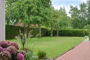 un giardino con fiori e alberi e un marciapiede di Ferienwohnung Sonnenberg, 25502 a Weener