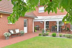 a brick house with a patio with a table and chairs at Ferienwohnung Sonnenberg, 25502 in Weener