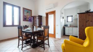 a dining room with a table and a yellow chair at Welcomely - Isole Apartments in Olbia