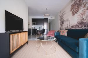 sala de estar con sofá azul y TV en Arco Macarena Suite, en Sevilla