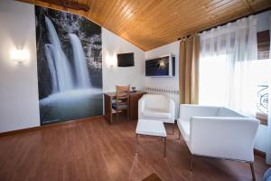 a living room with white chairs and a desk at Hotel La Barrosa in Abejar