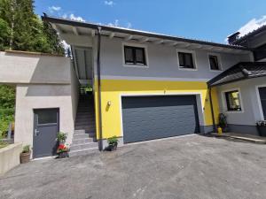 a yellow and grey house with a garage at Ferienwohnung Melanie in Kirchbach
