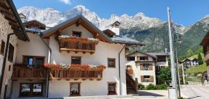 a building with flowers on the balconies in front of mountains at Stella Alpina Suite in Val di Zoldo
