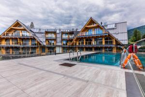 a person walking by a swimming pool in front of a building at Apartamenty Royal Resort Spa in Zakopane