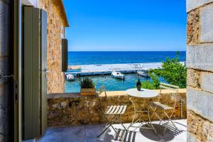 um pátio com uma mesa e cadeiras e o oceano em Selinitsa Residence Mani em Ágios Nikolaos