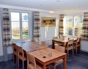 a dining room with two tables and chairs and windows at Hotel Restaurant Sunnmatt in Aeschi