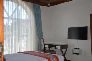 a bedroom with a bed and a desk and a window at Villa Asimba in Kigali