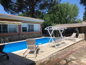 a swimming pool with two chairs and a swing at Renacer de los Sentidos in Pelayos de la Presa