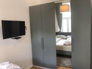 1 dormitorio con armario, TV y cama en PULSE OF VIENNA by JR City Apartments, en Viena