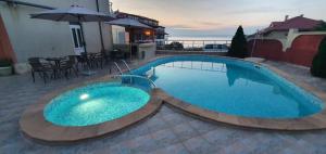 a large blue swimming pool with a table and umbrella at Hotel PERLA BEACH in Sozopol