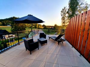 eine Terrasse mit Stühlen, einem Sonnenschirm und einem Tisch in der Unterkunft Hotel KORTUS in Jetřichovice