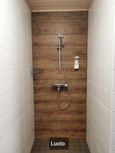 a shower in a bathroom with a wooden wall at Hamina Camping Pitkäthiekat in Hamina
