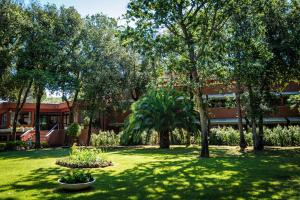a green yard with trees and a building at Park Hotel I Lecci in San Vincenzo