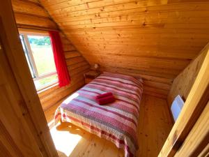 małe łóżko w drewnianym domku z oknem w obiekcie Žubītes w mieście Bērzgale