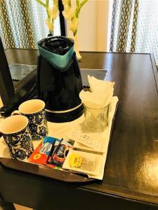 a table with a coffee pot and two cups on it at Atlas hotel in Islamabad
