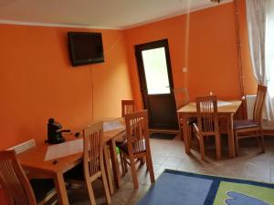a dining room with orange walls and wooden tables and chairs at Sóhegy Panzió in Praid