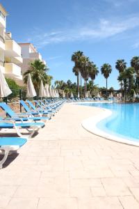 - une rangée de chaises longues et de parasols à côté de la piscine dans l'établissement Easy4Stay by Beach Resort, à Portimão