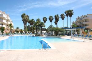 a large swimming pool with chairs and palm trees at Easy4Stay by Beach Resort in Portimão