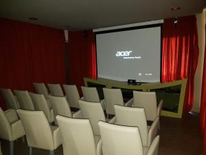 una sala de conferencias con sillas blancas y una pantalla en Hotel Platino Termas All Inclusive en Termas de Río Hondo