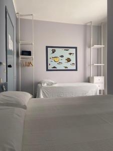 a white bedroom with two beds and a painting on the wall at Hotel Mambo in Laigueglia