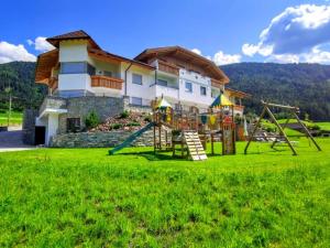 a playground in front of a house with a building at Residence Stefansdorf in Brunico