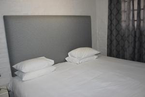 a white bed with two pillows on top of it at Riempie Estate Self-Catering in Oudtshoorn