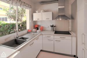 une cuisine avec des armoires blanches, un évier et une fenêtre dans l'établissement Casa Alena, à Santa Úrsula
