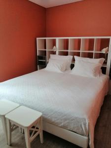 a bedroom with a large white bed with an orange wall at Sonetos do Tejo in Vila Nova da Barquinha