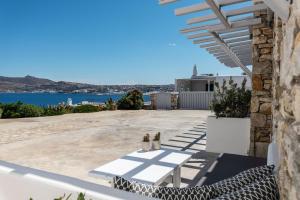 a patio with a view of the water and a house at Aegean View Apartments Mykonos in Agios Ioannis Mykonos