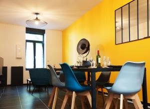 a dining room with yellow walls and a table and chairs at Casa Blanc Seau in Tourcoing