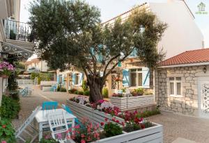 a tree in the courtyard of a house with flowers at Zeytin Arası Apart Otel in Ayvalık